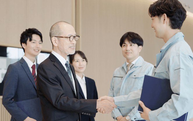工事完了後に関係者が握手し、竣工の引き渡しを行う場面